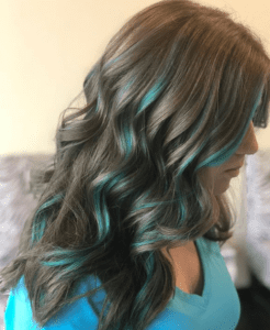 Girl with brown wavy hair with blue colored stripes